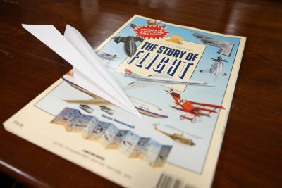 A paper airplane lands on The Story of Flight Booklet from the archives