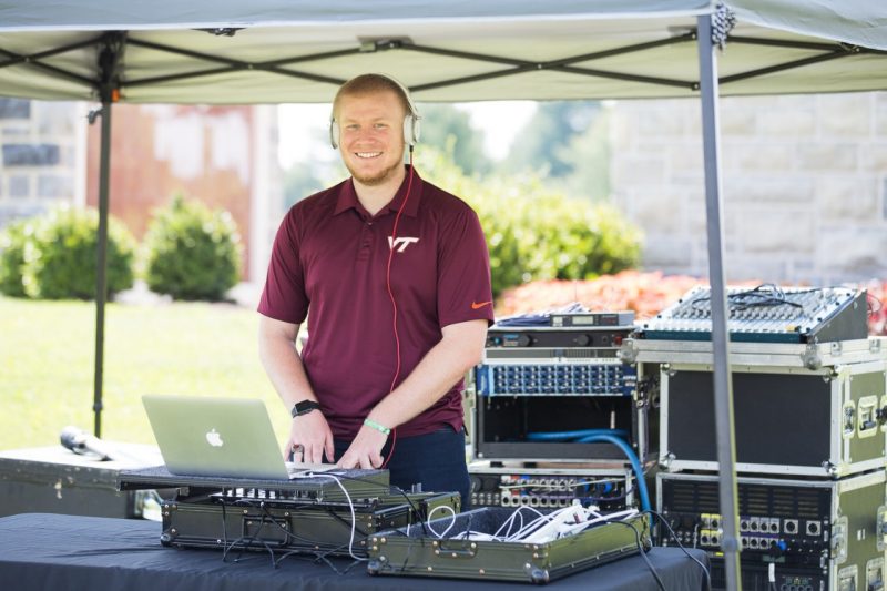 Cody Lopez poses in front of his DJ equipment at an event on campus.